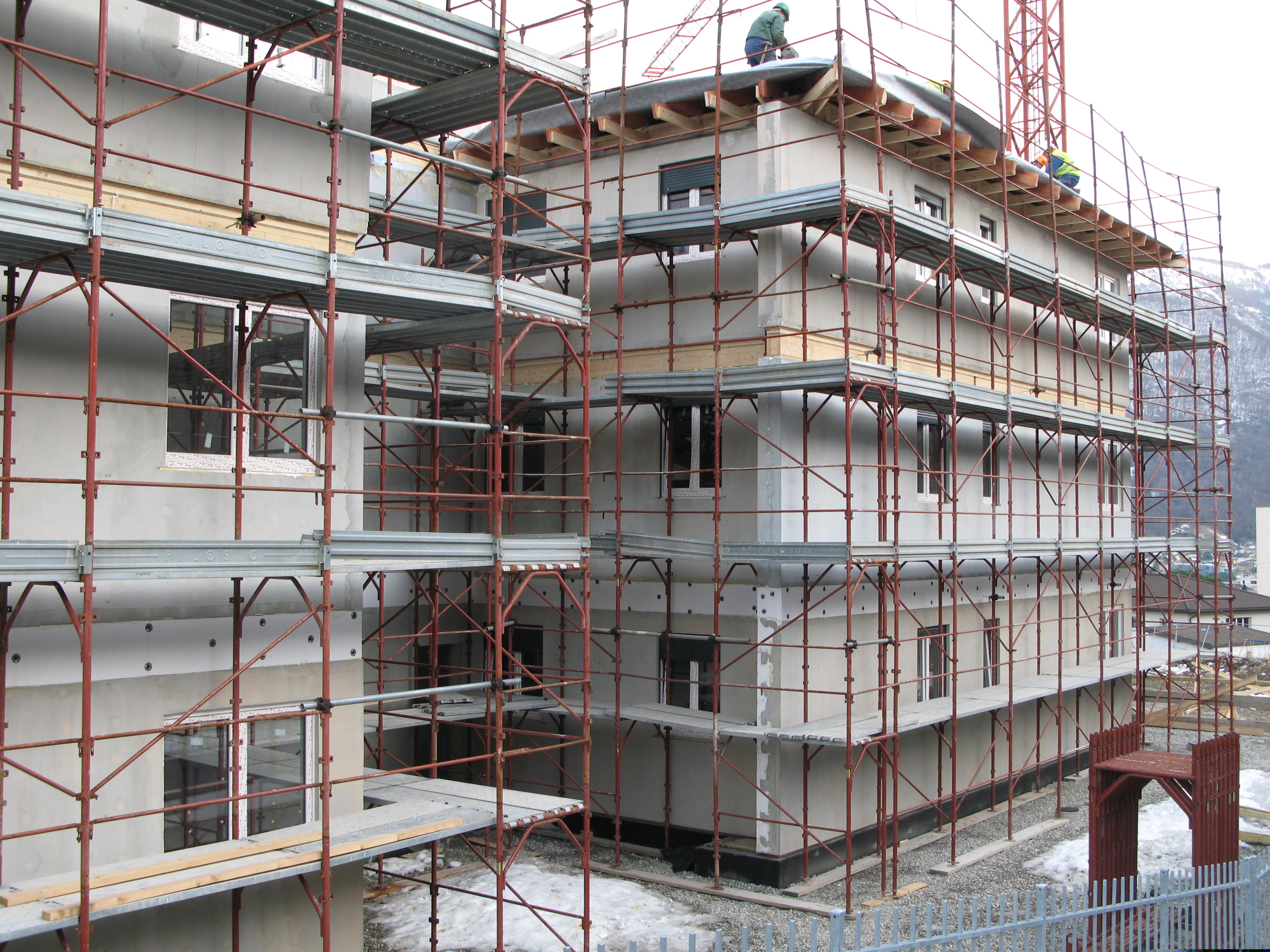 Montage van houten appartementsgebouw met steigers